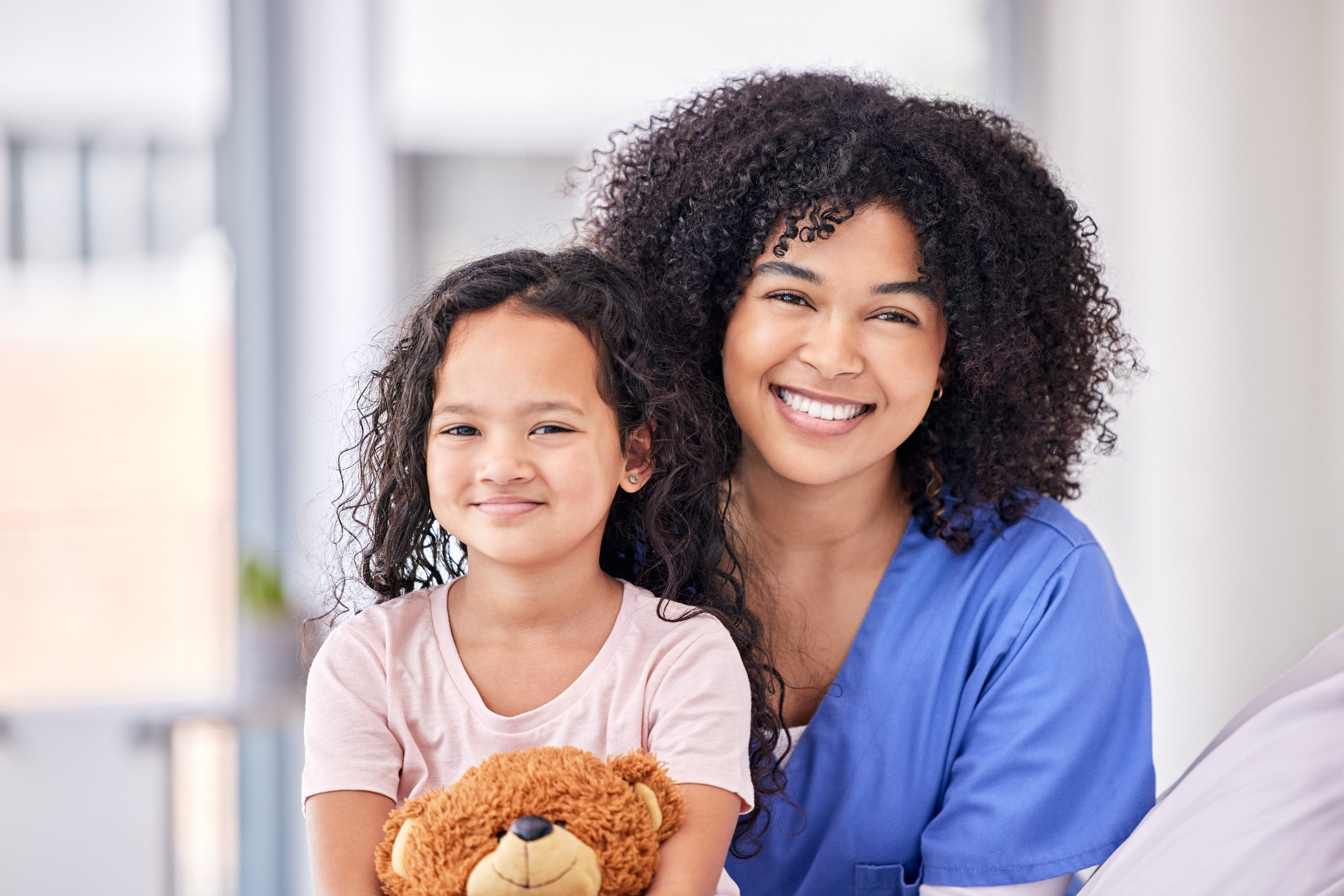 Child with a teddy bear supported by a care professional