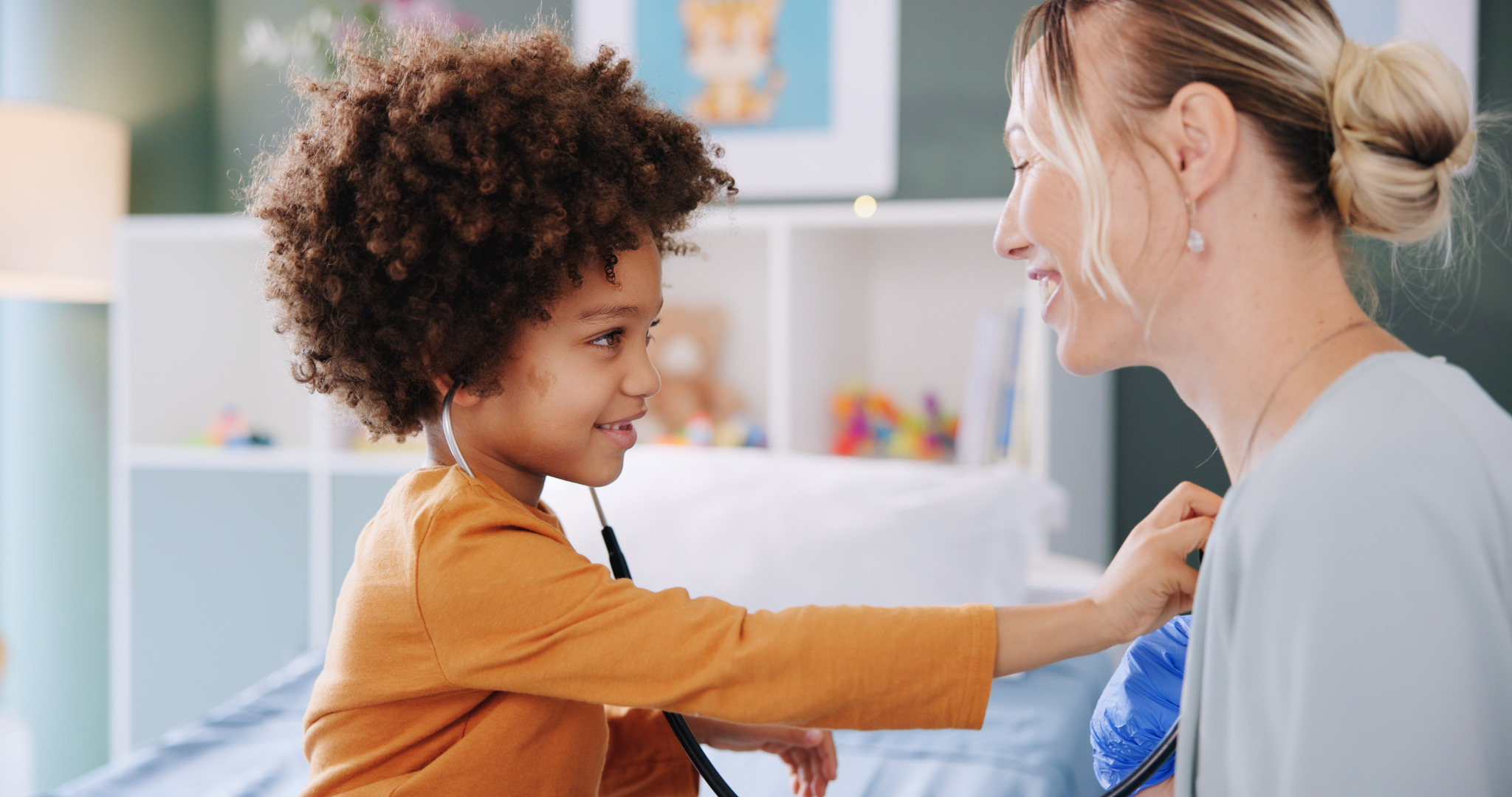 Child playfully using a stethoscope with a care professional